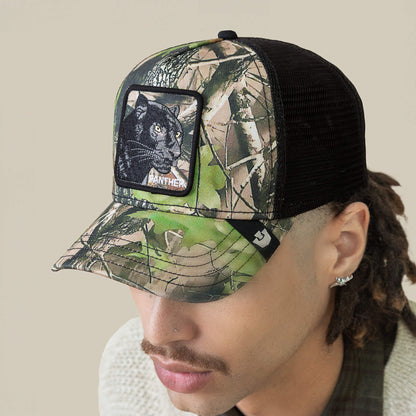 A person wears the Goorin Bros. Camouflage Panther cap, featuring deep woods camo, black mesh, and a patch with luxurious midnight-black panther embroidery.