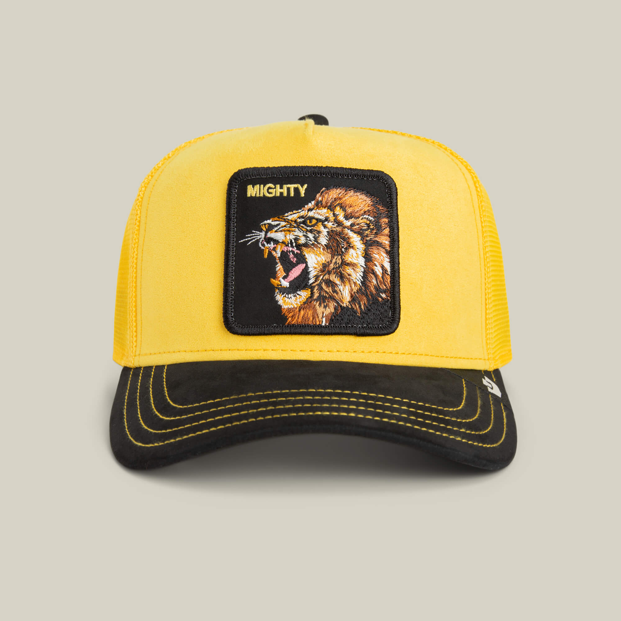 The Goorin Bros. Suede Lion trucker hat features a golden yellow crown, black brim, a lion patch, and MIGHTY embroidered above the roaring lion.