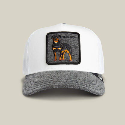 The Goorin Bros. Denim Bad Boy is a white and gray trucker cap with a patch showing an embroidered black and tan Rottweiler, perfect for fans of clean whites and classic style.