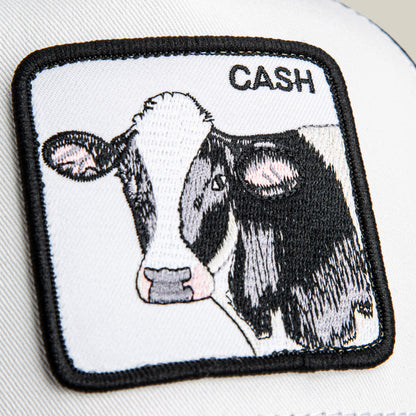 The Goorin Bros. Cash Cow Trucker features a bold patch with an embroidered black and white cow head and the word "CASH" in the top right—an ideal addition to any trucker hat collection.