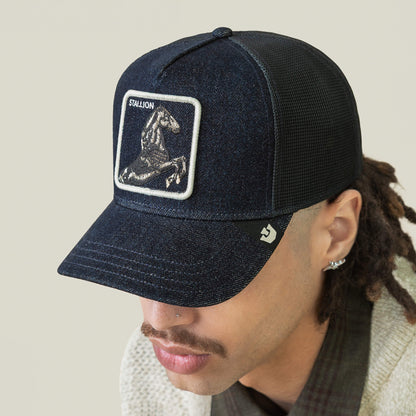 A person wearing a dark arena mesh Goorin Bros. Denim Stallion baseball cap with a horse patch labeled STALLION on the front, looking downward.