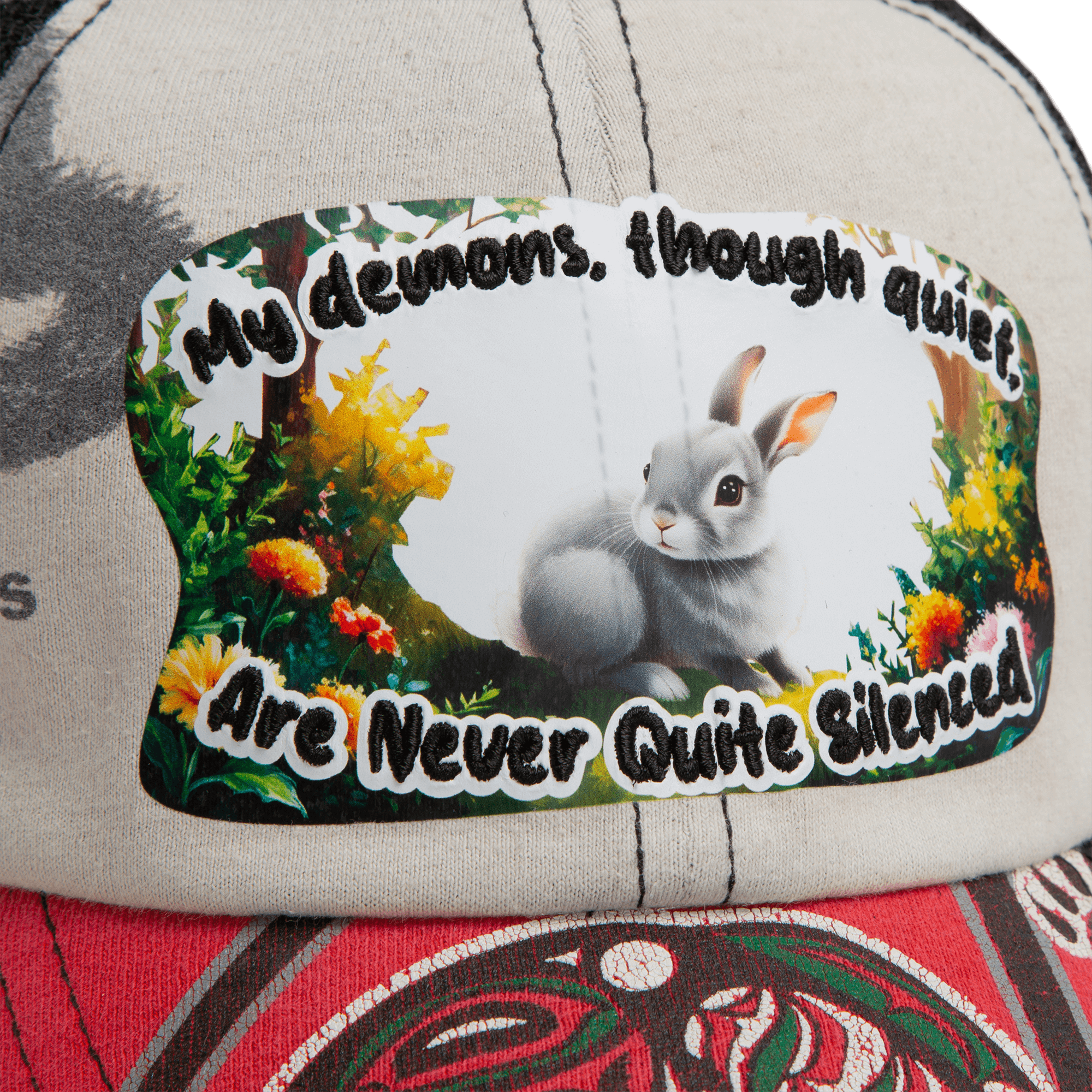 A close-up of the Lil Ronin hat by Goorin Bros., crafted from recycled tees, with a patch featuring a gray rabbit, vibrant plants, and the phrase "My demons, though quiet, are never quite silenced.