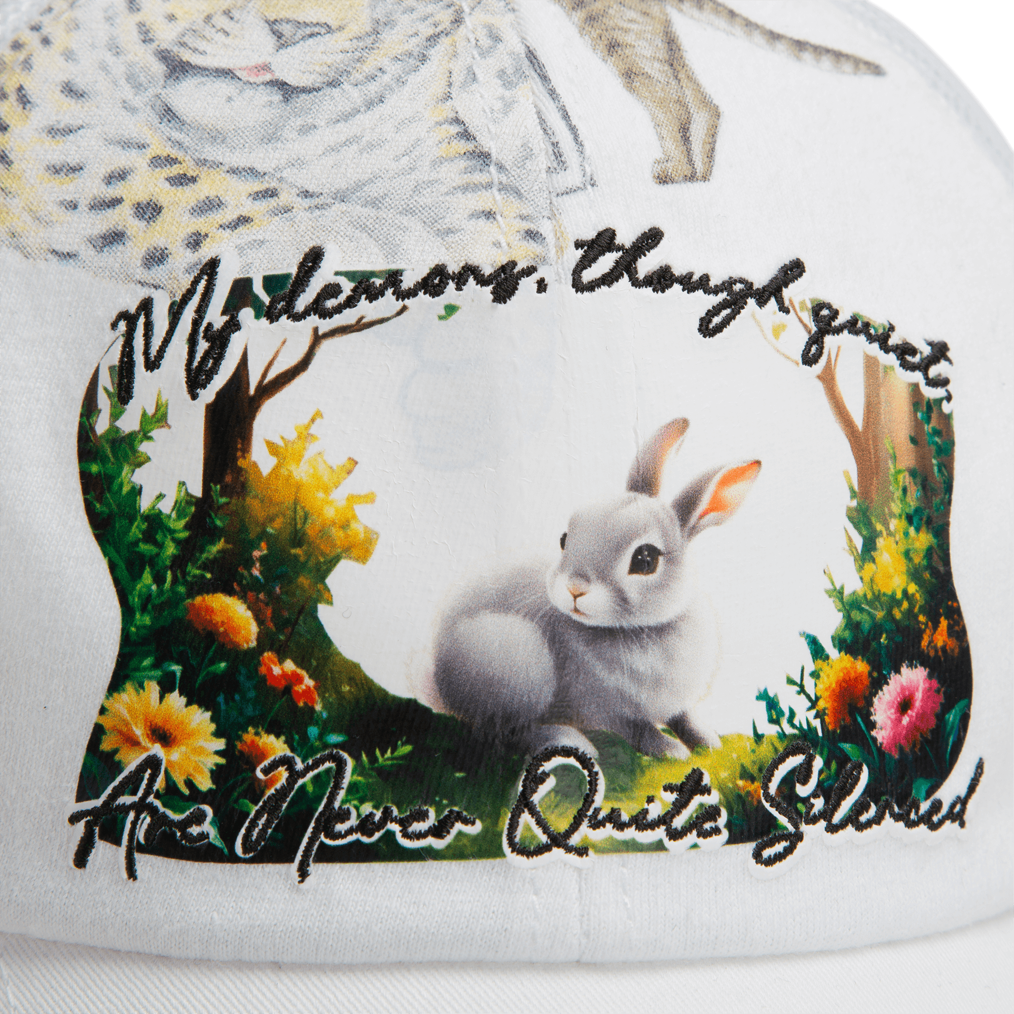 Close-up of a white fabric from Goorin Bros.' Lil Ronin collection, featuring a printed rabbit, floral accents, and the embroidered text: My demons, though quiet, are never quite silenced.