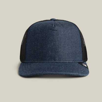 The Clean Denim Trucker by Goorin Bros. features a curved brim and black mesh back, crafted in the USA and shown on a beige background.