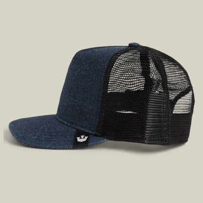 The Goorin Bros. Clean Denim Trucker cap features blue denim, a black mesh back, flat brim, and a side black tag with a white crown logo. Made in the USA and shown on a neutral background.