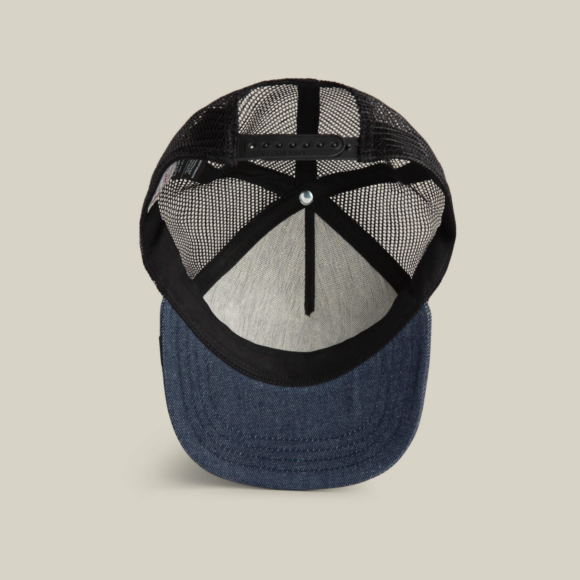 The Goorin Bros. Clean Denim Trucker hat features a mesh back, an adjustable snap closure, and a clean denim curved brim as seen from the underside.