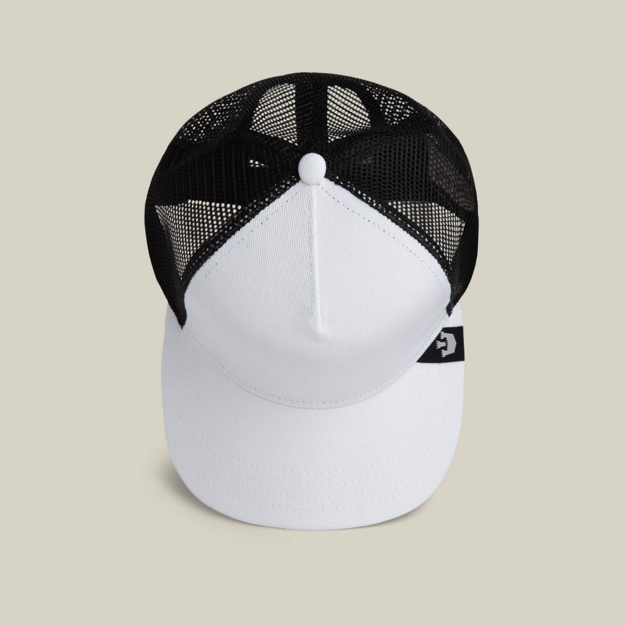 The Goorin Bros. Clean Denim Trucker is a white and black denim hat with a mesh back and a small black tag featuring a white logo on the side, displayed against a plain beige background.