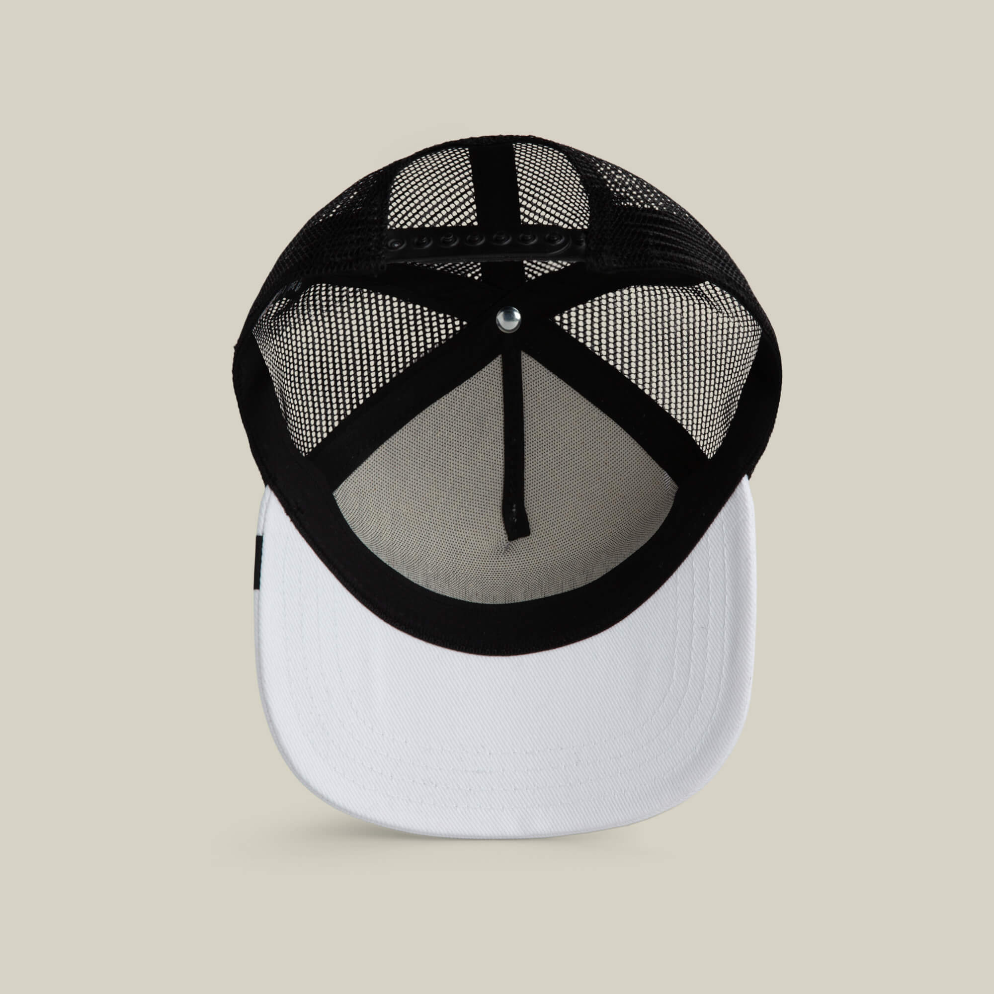 The Clean Denim Trucker by Goorin Bros. features a black mesh back, white front panel and brim, shown from below on a beige background. This hat updates classic style with a modern touch.