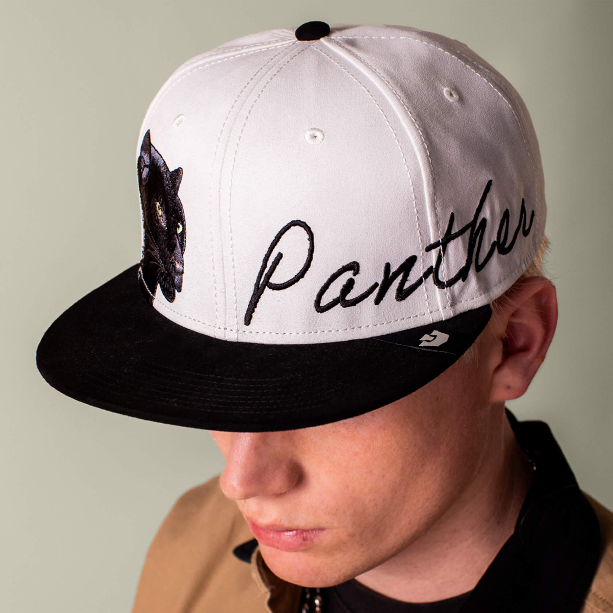 A person wearing the Goorin Bros. 6-Panel Panther Script cap in black and white, featuring an embroidered panther patch and the word "Panther" on the front.