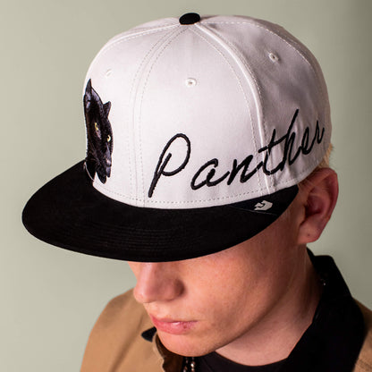 A person wearing the Goorin Bros. 6-Panel Panther Script cap in black and white, featuring an embroidered panther patch and the word "Panther" on the front.
