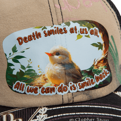A close-up of the Lil Samurai cap from Goorin Bros.' Storybook collection, featuring a patch with a bird in a nest and the text: "Death smiles at us all. All we can do is smile back.