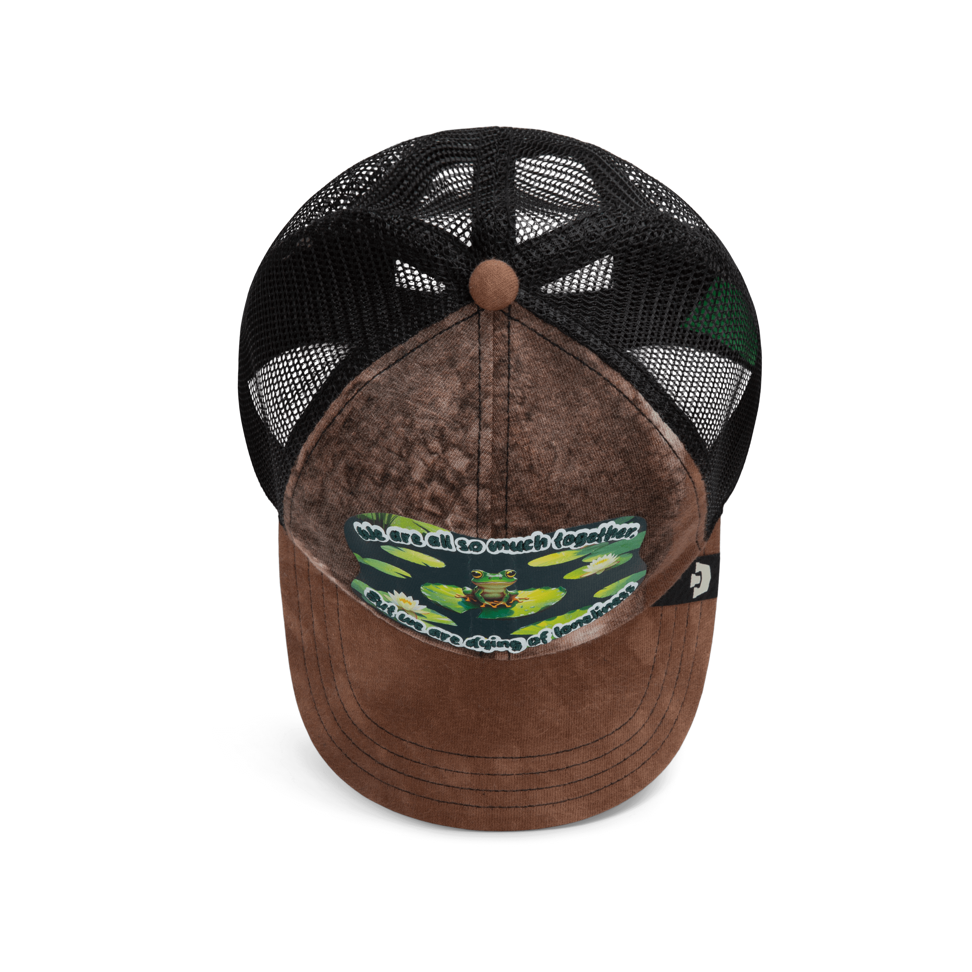 The Lil Sohei by Goorin Bros. is a brown and black trucker hat from the Storybook collection, featuring illustrated frogs, a mesh back, and the phrase: We are all so much together...but we are dying of loneliness.