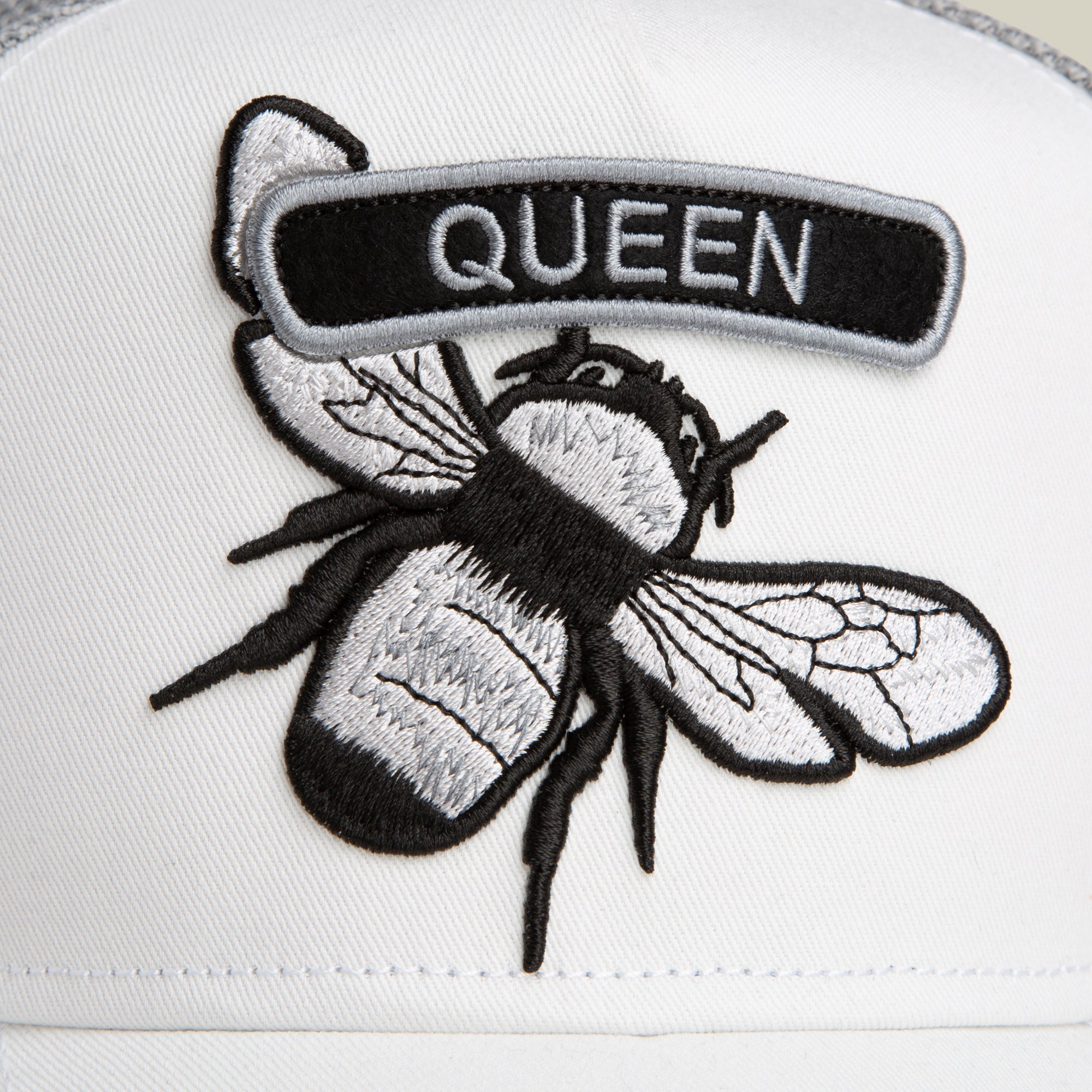 Embroidered "QUEEN" bee patch by Goorin Bros. from the Classic Rocker - Queen collection, set on white fabric—ideal for adding flair to your white or grey rocker jacket.