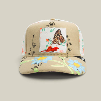 The Vol. 1 - Quiltbag: Live hat by Goorin Bros. in SCOUT features blue and orange floral embroidery and a bold butterfly patch on the front panel.