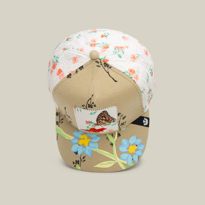 A Goorin Bros. Vol. 1 - Quiltbag: Live OG Trucker hat in beige and white features floral embroidery and a butterfly design on the front, shown against a neutral background.
