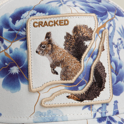 The Break The Mold hat by Goorin Bros. features blue floral patterns, a jagged patch with a squirrel, and the word CRACKED—making it the perfect accessory to showcase your unique style.
