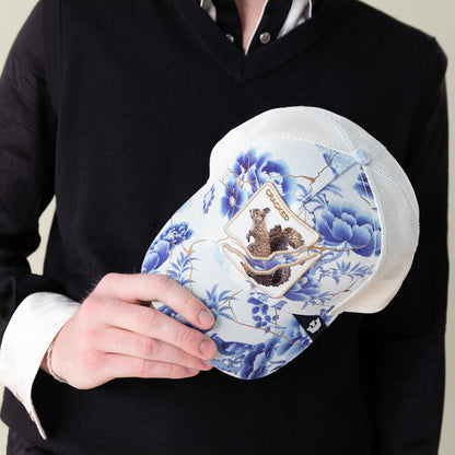 A person in a black sweater holds the "Break The Mold" blue and white floral baseball cap by Goorin Bros., featuring an embroidered beaver patch and the word Canada, highlighting unique personality.