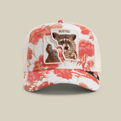 The Goorin Bros. Break The Law cap in CHALK features a floral pattern and a split patch with a raccoon and the word “BUSTED,” as if the patch was once whole.