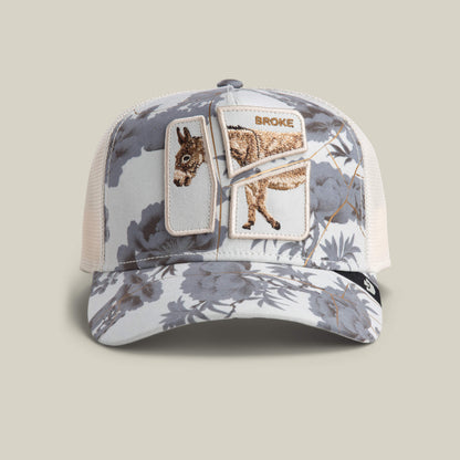 The Goorin Bros. Break The Bank mesh baseball cap in CHALK features a floral pattern and an embroidered donkey patch labeled BROKE—an amusing novelty gift for anyone with a playful sense of humor.