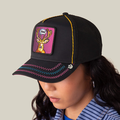 A person wearing the Goorin Bros. Earned Media cap, featuring black mesh, neon stitching, and a Pop Art-style deer patch on the front.