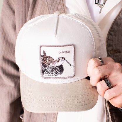 A person holding the Goorin Bros. Suede Rattlesnake hat, featuring a white and beige design, suede brim, and a rattlesnake patch with "OUTLAW".