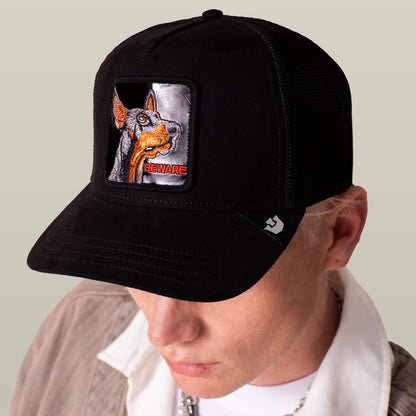 A person wears the Goorin Bros. Black Out Doberman cap, a black suede baseball hat featuring a Doberman dog patch with "BEWARE" stitched below the image.