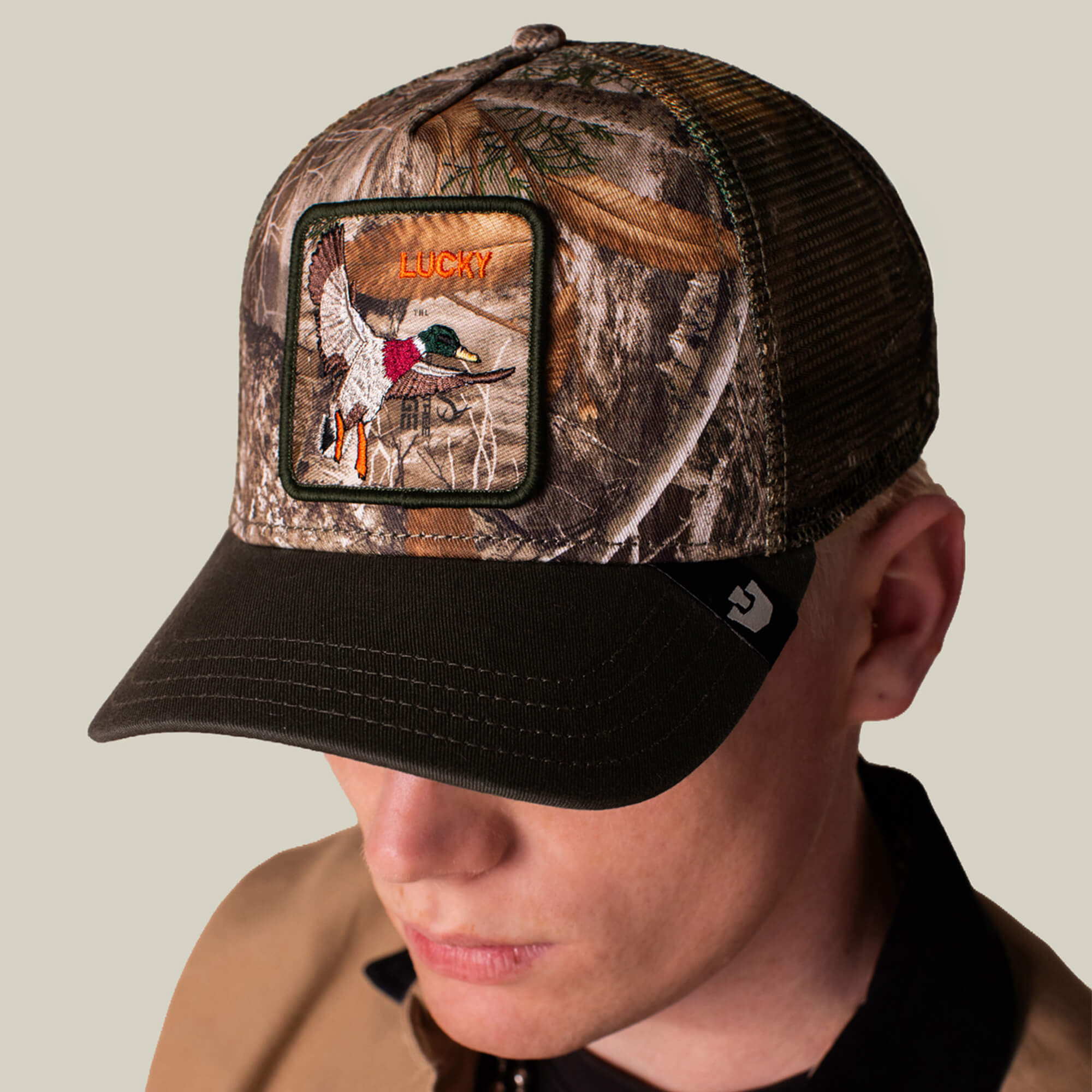 A person wearing the Goorin Bros. Realtree Edge Lucky Duck mesh baseball cap, featuring a camo colorway and a duck patch with the word "LUCKY" embroidered.
