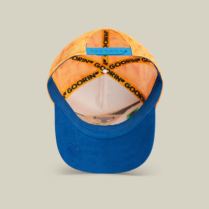 A blue and orange trucker hat shown from above, featuring Goorin’s bold hat designs with a mesh back, fabric front, interior tags, and a GOORIN branded inner band.