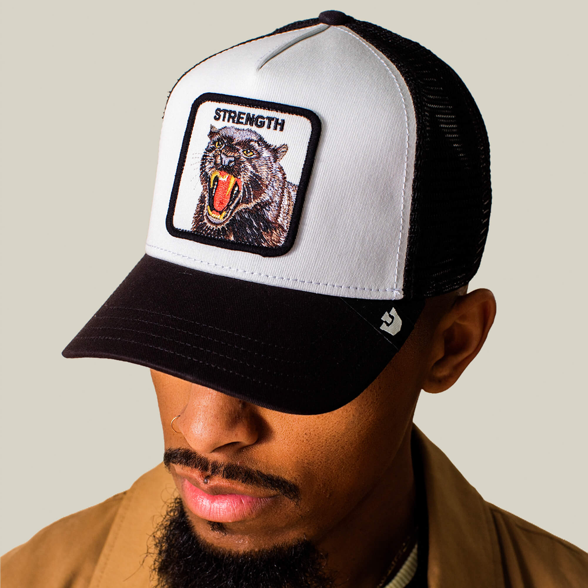 A man wears the Goorin Bros. Strength Panther cap, a black and white hat featuring a roaring panther patch labeled "STRENGTH" on the front.