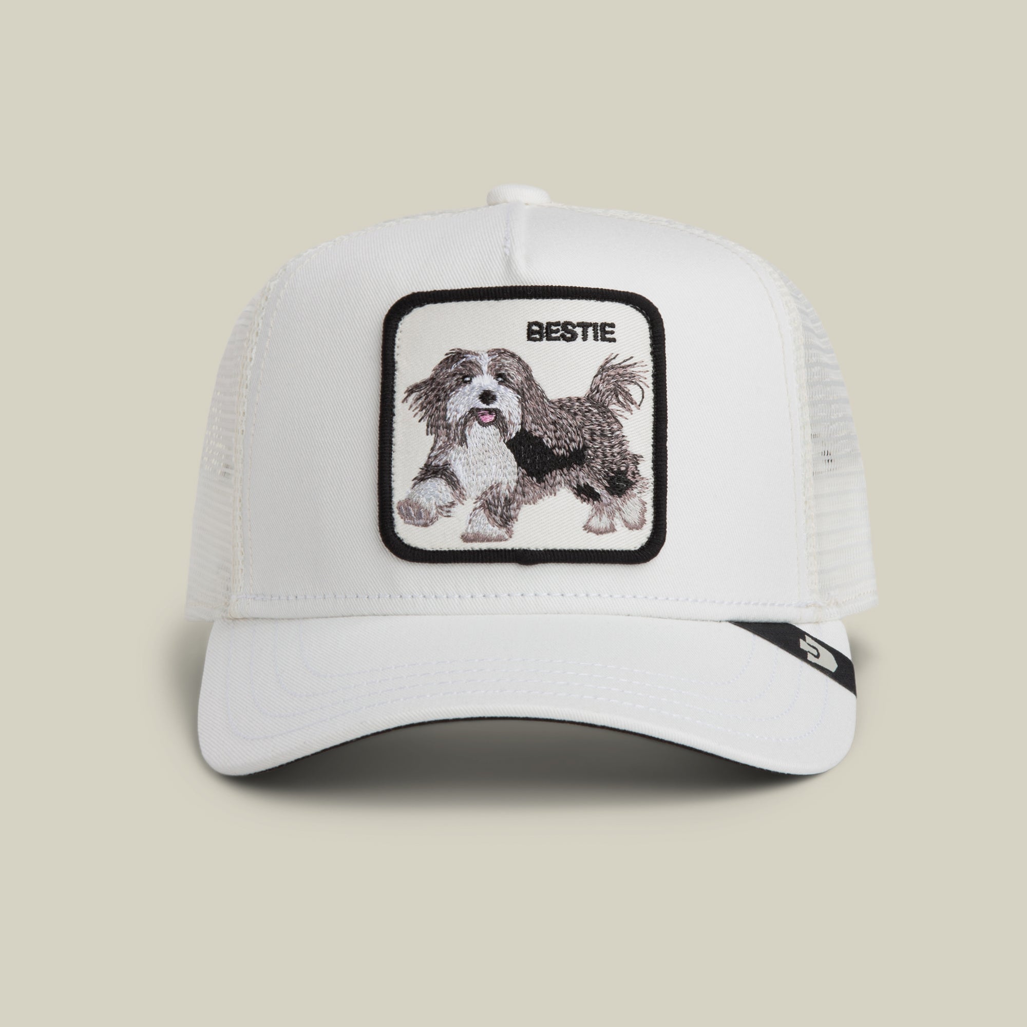The Goorin Bros. Bestie Trucker in Dust features a white mesh design and a square patch with an embroidered dog and the word "BESTIE" above it.