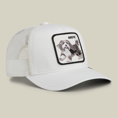 The Goorin Bros. Bestie Trucker is a white mesh trucker cap with a patch featuring an embroidered running dog and the word “BESTIE” above it.