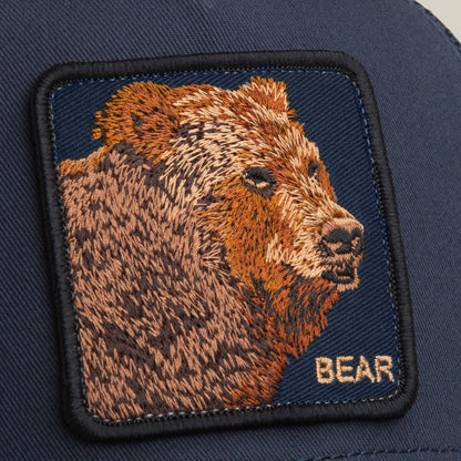 A close-up of the Bear Trucker by Goorin Bros., showing a detailed bear patch with "BEAR" in yellow embroidery—an ideal way to add character to your favorite navy trucker hat.