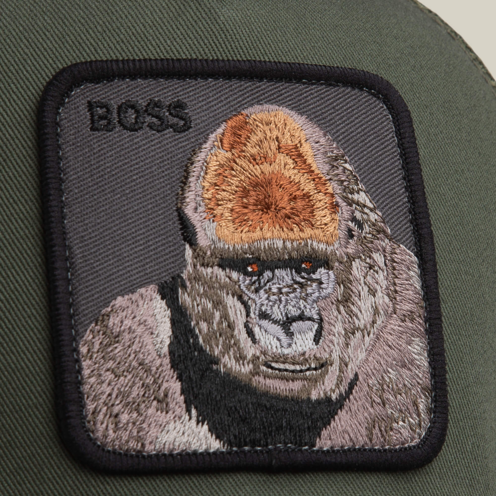 The Goorin Bros. Boss Trucker hat features a bold fabric gorilla patch with "BOSS" embroidery on deep olive, making it a standout accessory.