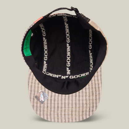 The Goorin Rework Camper by Goorin Bros. is a beige plaid recycled camp cap with black interior lining, GOORIN branding on the inside seams, and a metal pin near the brim. This limited edition piece is made in the USA.