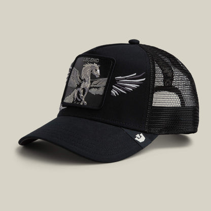 The Wings Legend trucker hat by Goorin Bros. features black mesh and a front patch with a Pegasus graphic labeled “Legend,” along with intricately embroidered wings on the sides, showcased against a plain beige background.