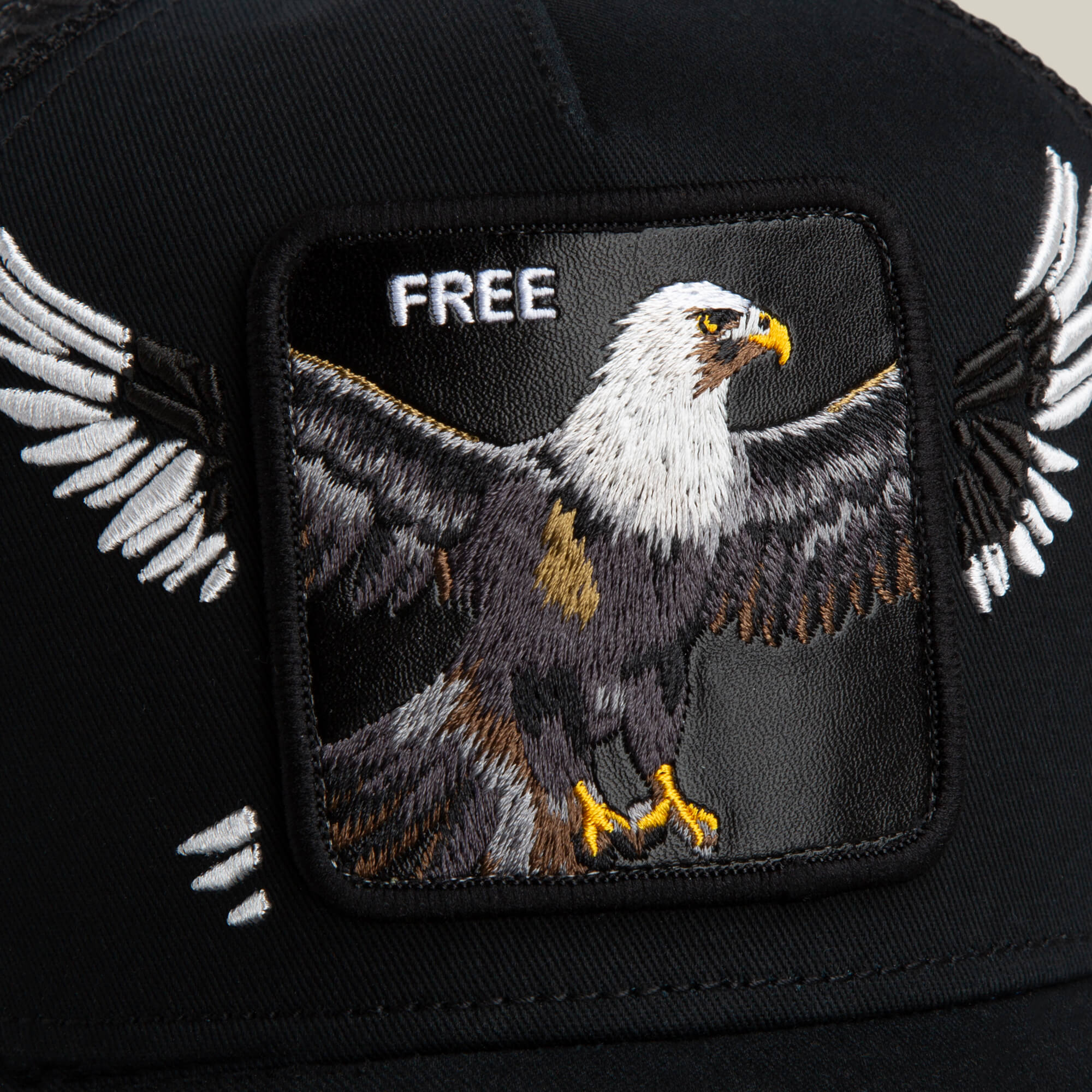 Close-up of the Goorin Bros. Wings Free black hat, featuring an embroidered patch with a bald eagle spreading its wings and the word "FREE" above.