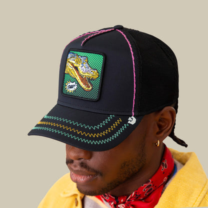Wearing Goorin Bros.' "Crackle and Pop, Brother"—a black mesh cap with neon stitching and a gator patch—alongside a red bandana and yellow jacket channels bold Pop Art vibes.