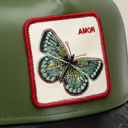 The Goorin Bros. Amor features a green leather surface, an embroidered butterfly patch with "AMOR" in red text and stitching—perfect to match with your favorite AMOR jewelry.