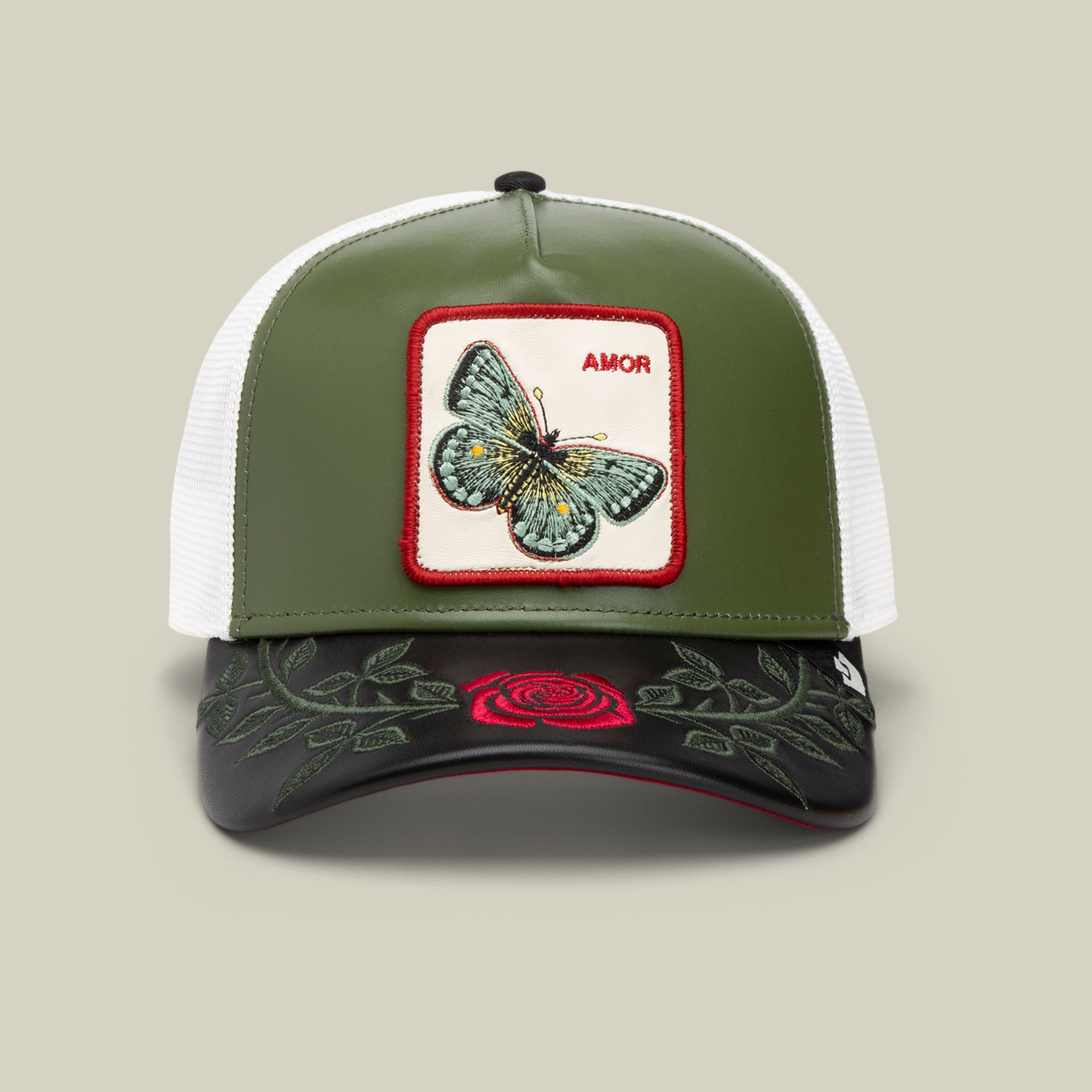 The Goorin Bros. Amor trucker hat in PALM features a butterfly patch labeled AMOR, inspired by our jewelry, and an embroidered red rose with green leaves on the black brim—perfect for your next Friday drop!.