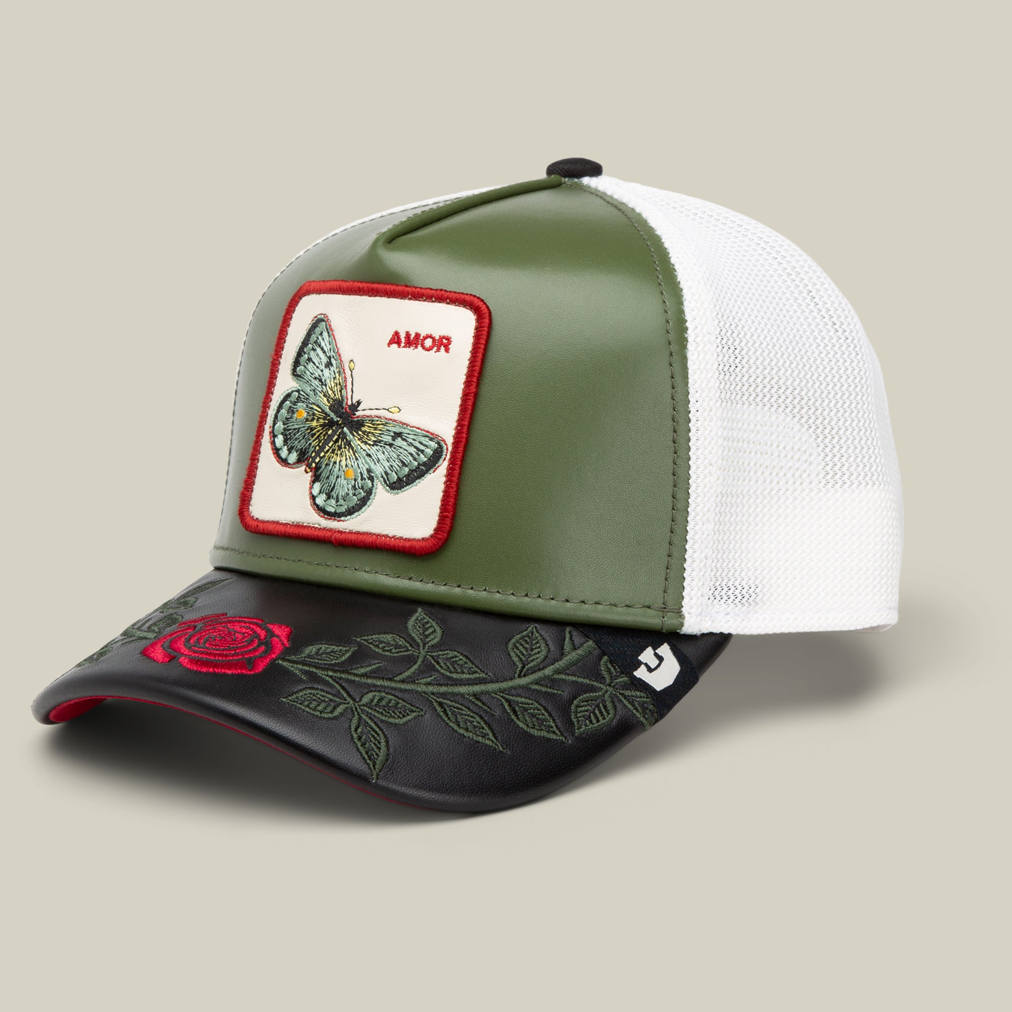 The Amor trucker hat by Goorin Bros. features green and white panels, a butterfly patch labeled "AMOR," and a red rose on the black brim—perfect to pair with your favorite love-themed jewelry or necklace.