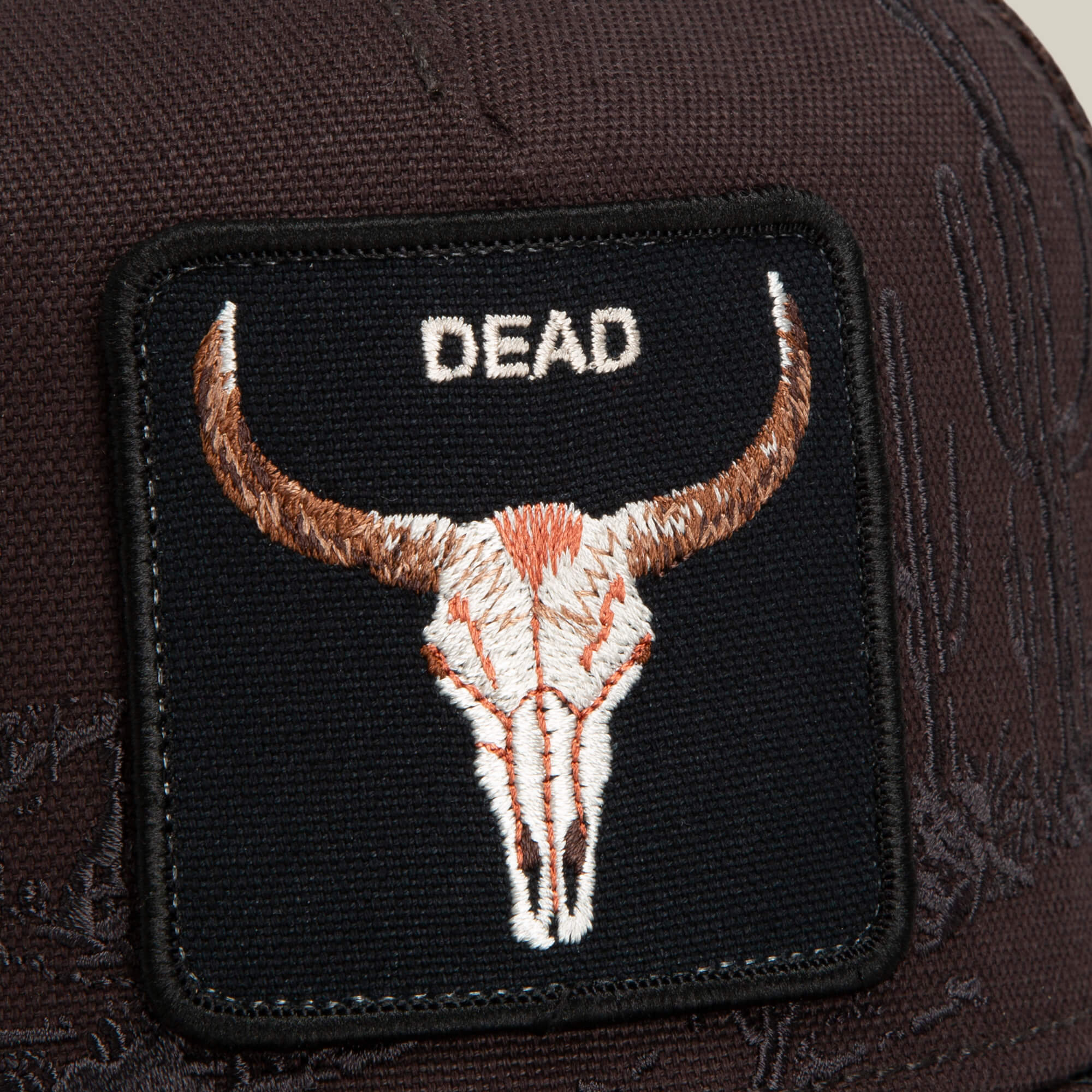 A close-up of the Goorin Bros. Badlands Skull patch, featuring an embroidered bull skull and the word "DEAD" in white letters on a dark brown fabric background.