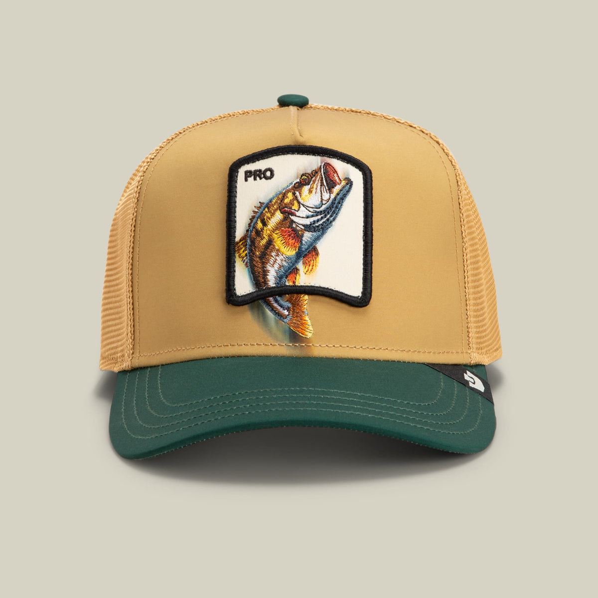 The Goorin Bros. Migration Pro trucker hat features a tan mesh back, dark green bill, and embroidered fishing patch with a jumping fish design on the front, displayed against a neutral studio background.