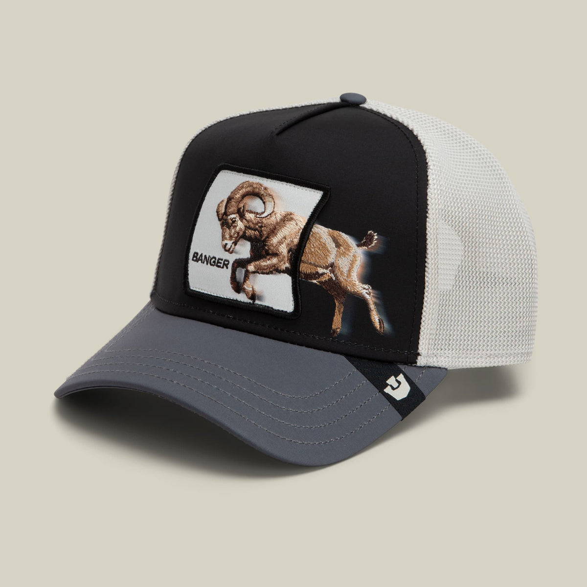 The Goorin Bros. Migration Banger trucker hat features a black front panel with embroidered goat patch labeled "Banger," white mesh back, and gray bill against a neutral background.