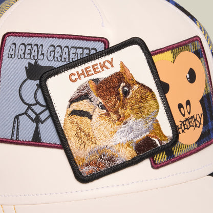 The Goorin Bros. Cheeky trucker hat features a cream and white crown with burgundy-trimmed embroidered patches, including a winking squirrel with "Cheeky" text and humorous character graphics.