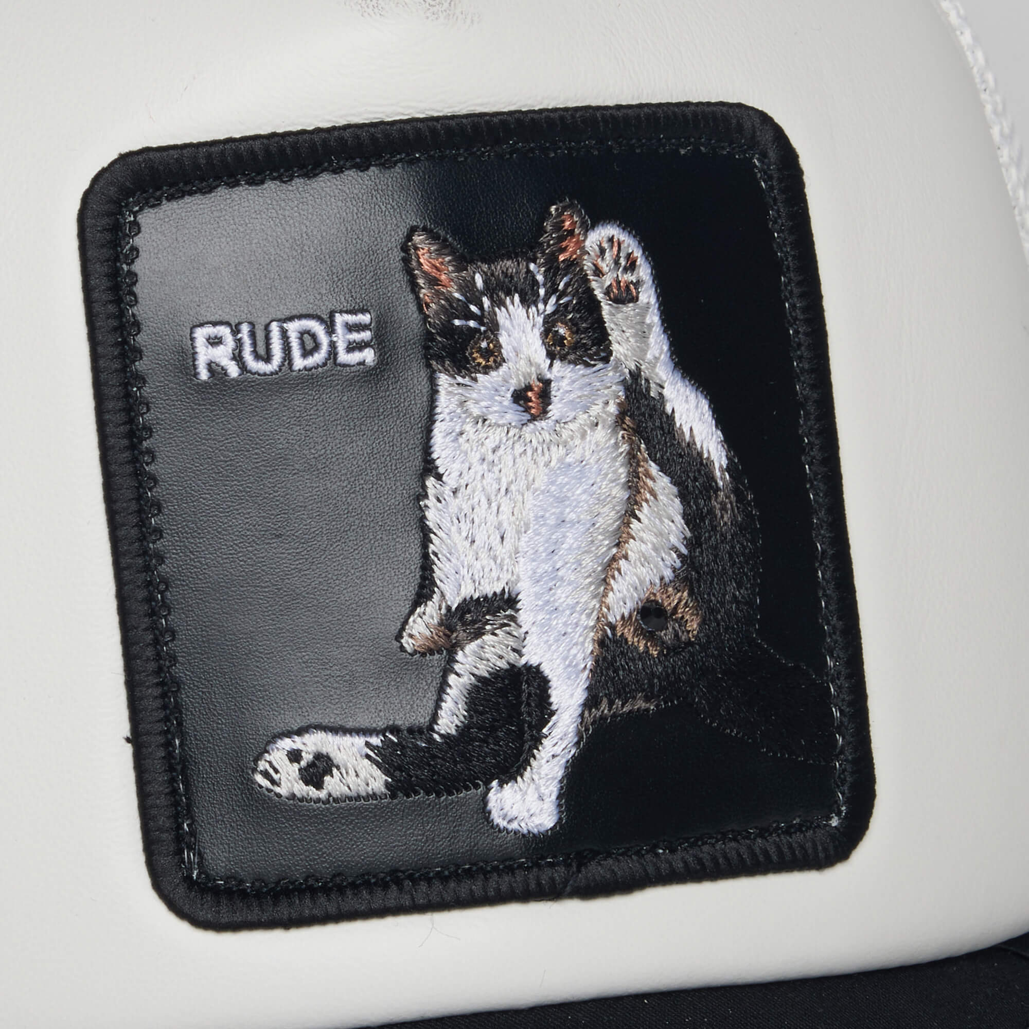 The R U Done Eating? patch by Goorin Bros. features a cheeky embroidered black and white cat grooming itself on a white background, with the word RUDE adding to its playful vibe.