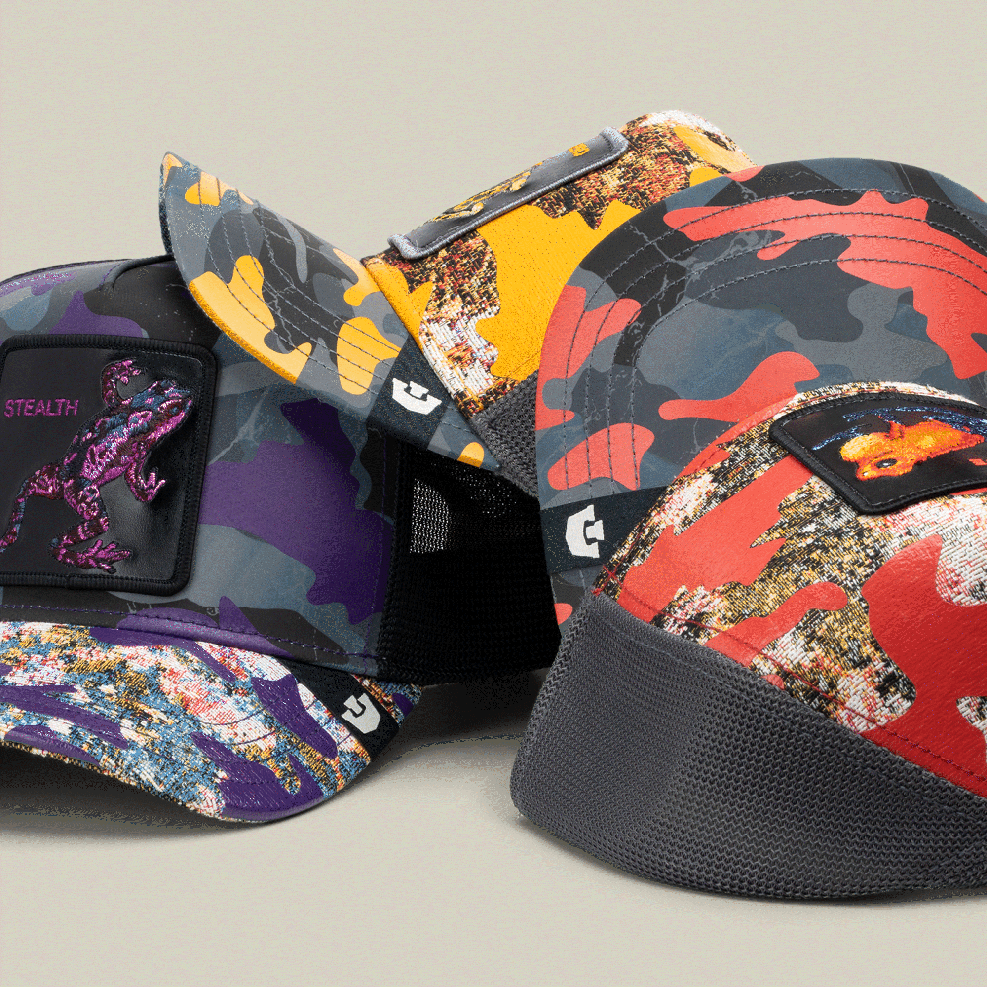 Four colorful "Knight in Sliming Armor" baseball caps by Goorin Bros., each with bold Hero patch or dino design, are displayed against a neutral background.
