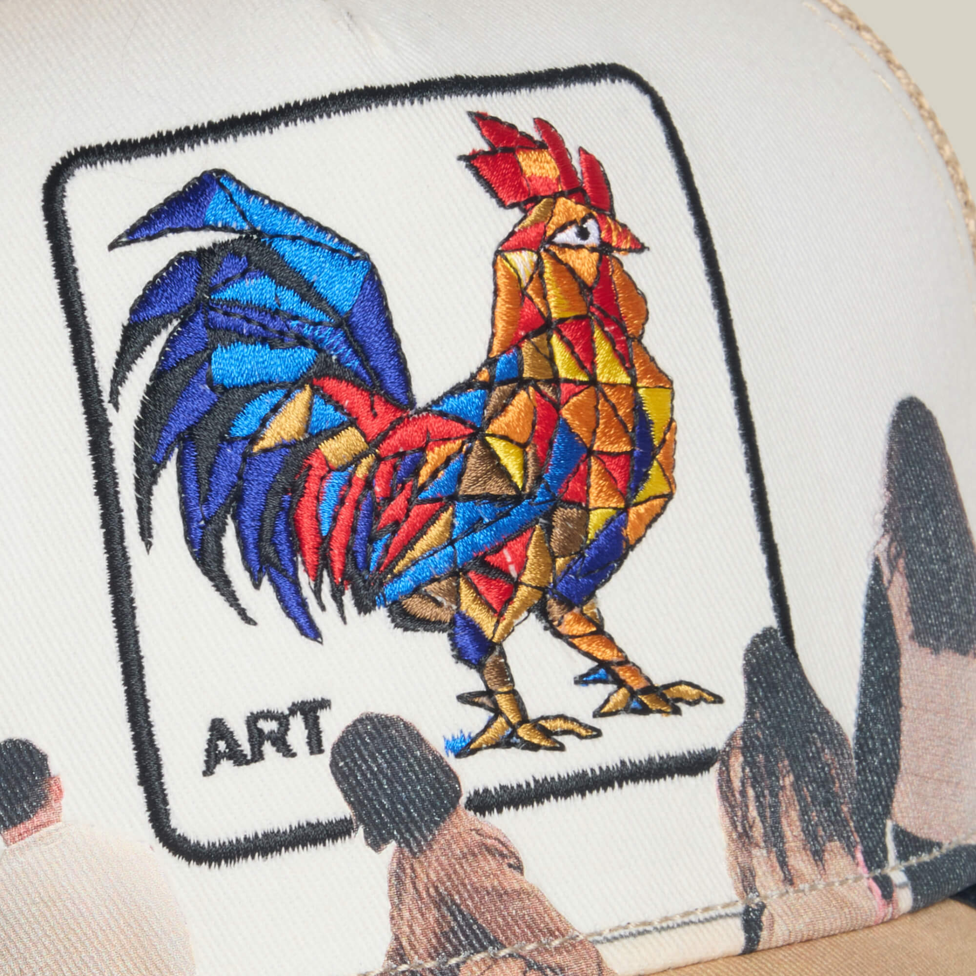 The Hey, I Like It! Picasso! hat by Goorin Bros. is white and showcases a colorful Picasso-style rooster patch labeled ART, with digital print embroidery of people standing and gazing upwards below the patch.