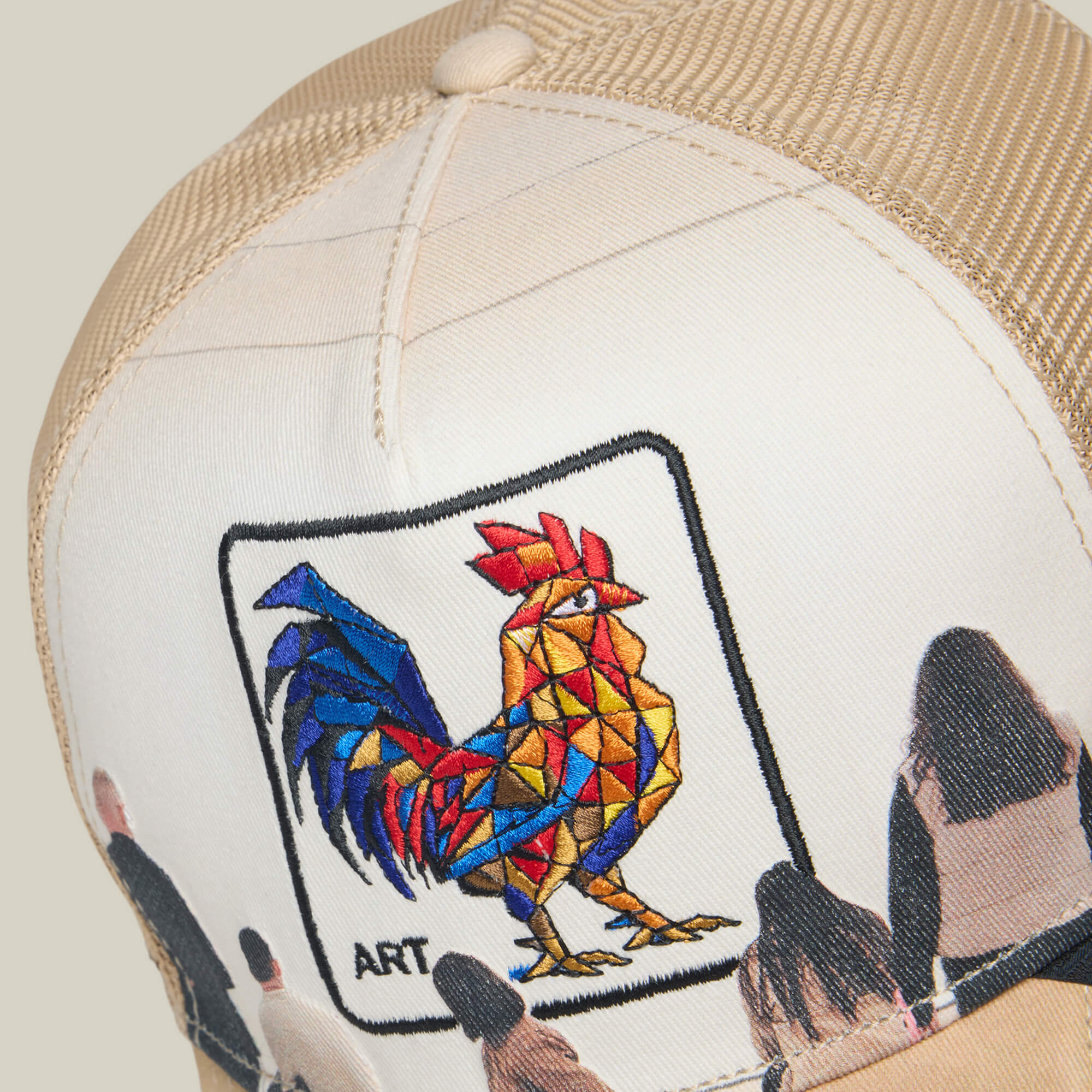 The Goorin Bros. "Hey, I Like It! Picasso!" hat is a beige trucker cap with a geometric rooster and the word ART above people figures, inspired by Picasso’s cubist style and finished with digital print embroidery.