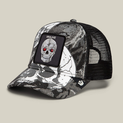 The Bone Head Unalive trucker hat by Goorin Bros. features a bold black and white skull print with red gem-like eyes, a breathable mesh back, and a signature UNALIVE patch.