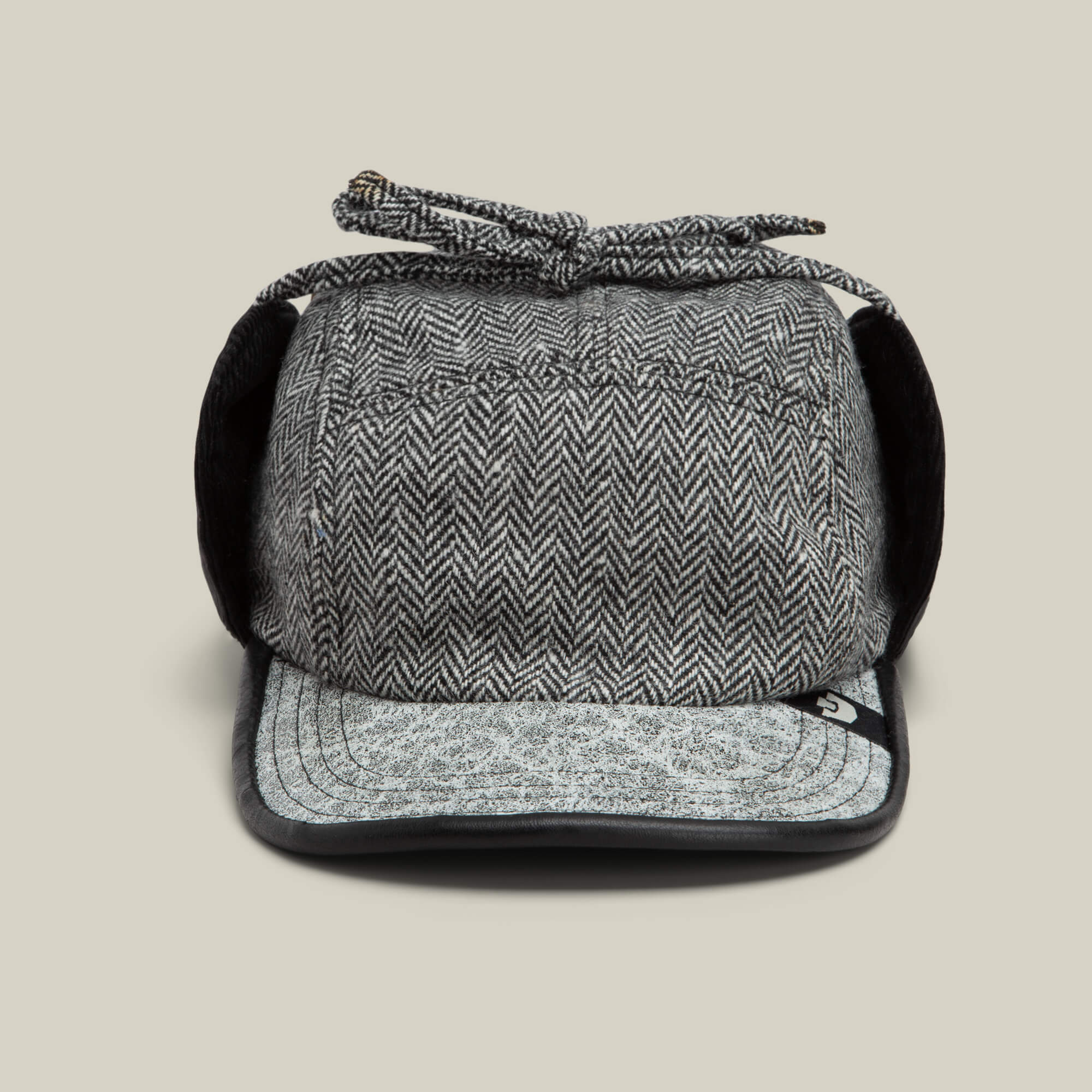 The Goorin Bros. Frazier Lake trapper hat in OIL features herringbone wool, fold-down ear flaps, a short brim, and a tied string on top, shown facing forward on a plain background.